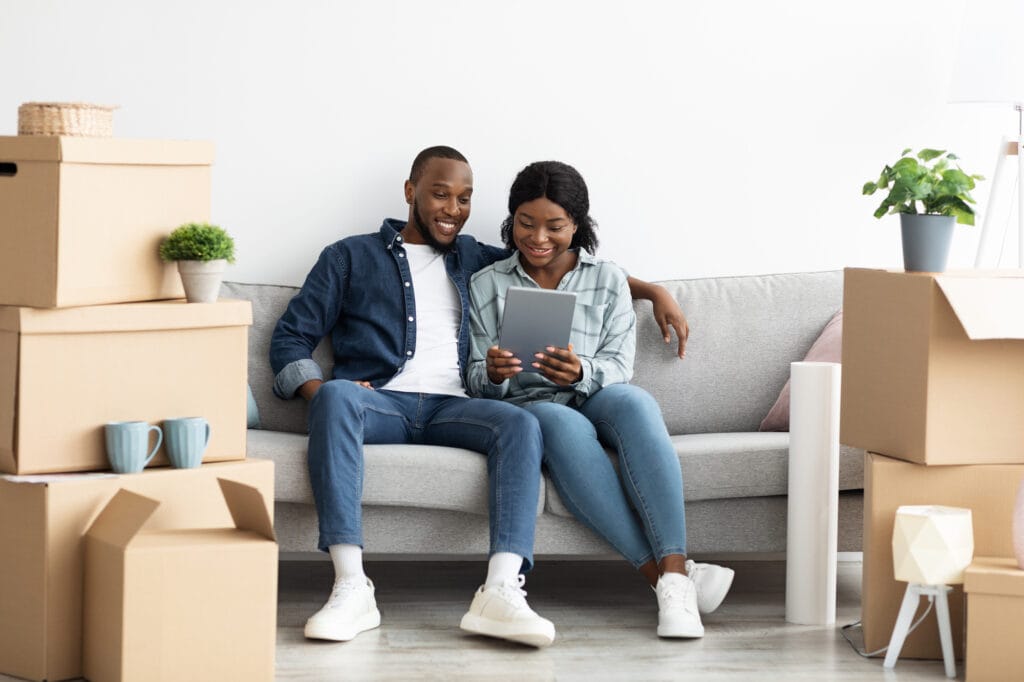 happy black couple using digital tablet together after moving to new home