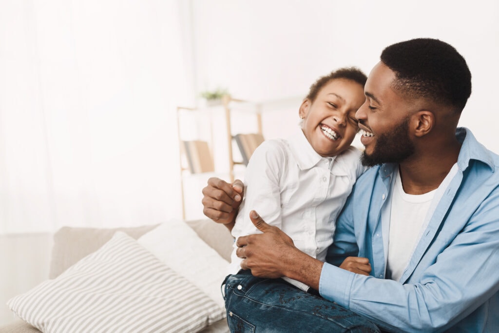 afro father tickling daughter, having fun and playing at home