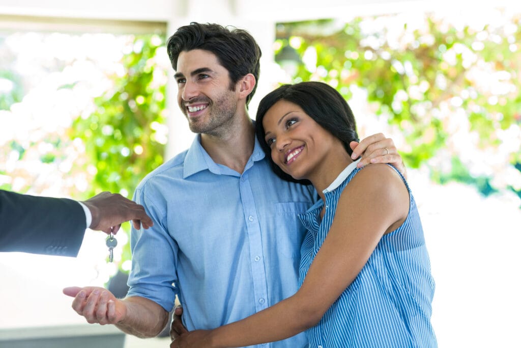 real estate agent giving house keys to the couple at home