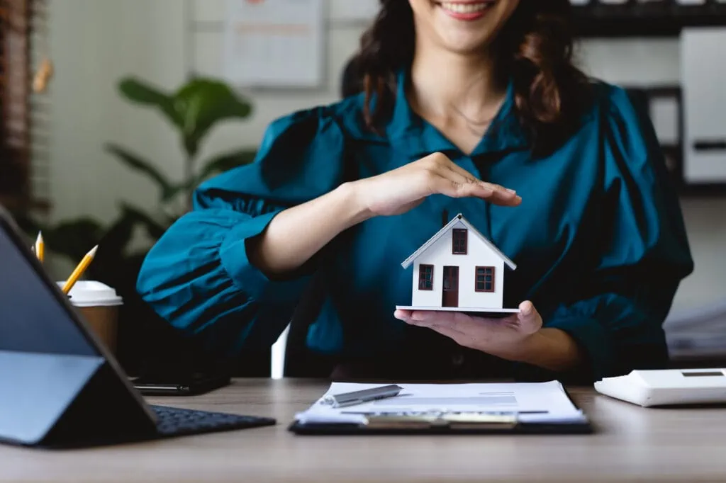 businesswoman use their hands to protect the red roofs, the concept of protecting houses using the gestures and symbols of real estate investors, taking care of credit and contracts.